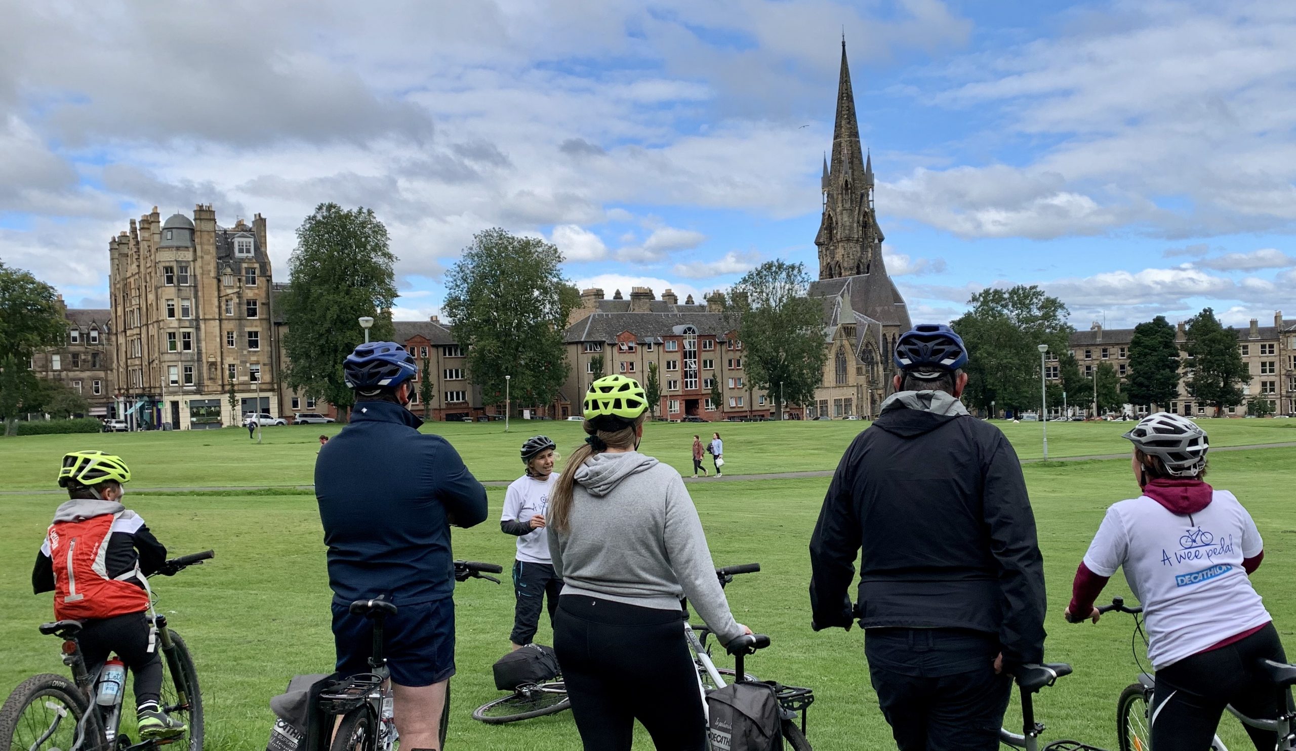 A wee pedal: Edinburgh Cycle Tours. The image show a group of people on a cycle tour, standing looking at Brunsfield Links