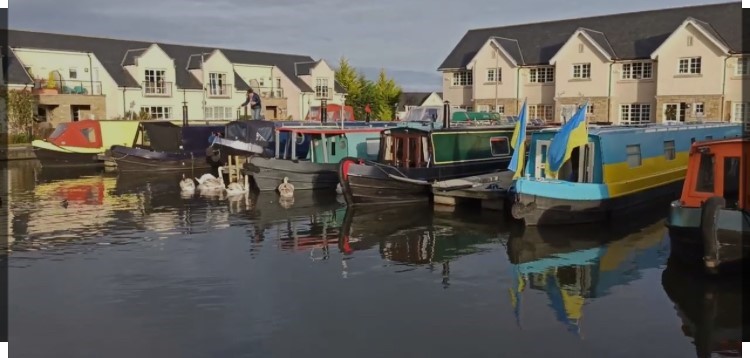 Picture of Ratho Marina, there are a number of canal boats in the foreground, with houses in the background